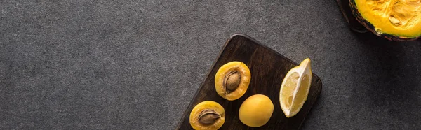 Top view of yellow fruits and pumpkin on wooden cutting boards on grey textured background, panoramic shot — Stock Photo