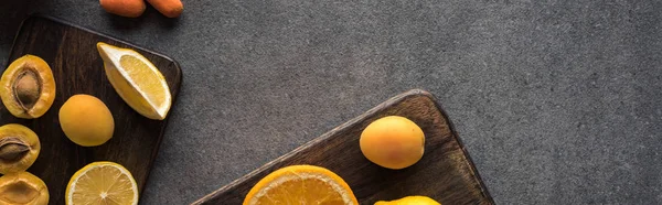 Top view of yellow fruits on wooden cutting boards on grey textured background, panoramic shot — Stock Photo