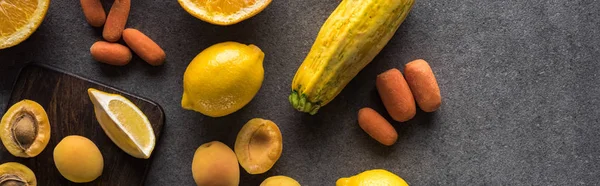 Ansicht von gelbem Obst und Gemüse auf hölzernen Schneidebrettern auf grauem strukturiertem Hintergrund, Panoramaaufnahme — Stockfoto