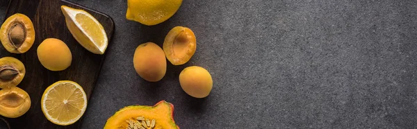 Top view of pumpkin, apricots and lemon on wooden cutting boards on grey textured background, panoramic shot — Stock Photo