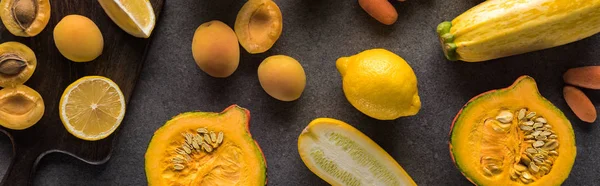 Top view of yellow fruits and vegetables on wooden cutting boards on grey textured background, panoramic shot — Stock Photo