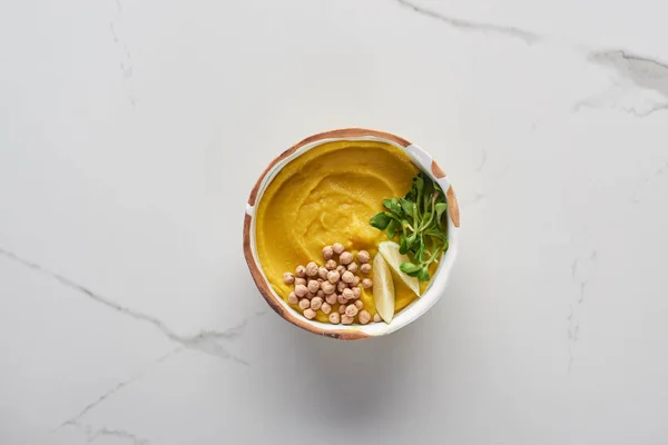 Vista superior de la sopa de calabaza molida otoñal en un tazón en la superficie de mármol - foto de stock