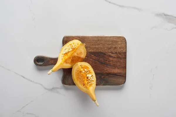 Top view of wooden cutting board with pumpkin on marble surface — Stock Photo