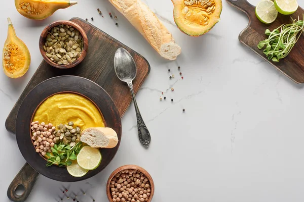 Vue de dessus de la soupe de citrouille en purée automnale près des ingrédients sur la surface du marbre — Photo de stock