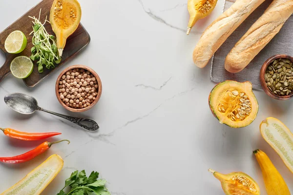 Top view of autumnal ingredients for pumpkin soup and baguette on marble surface — Stock Photo