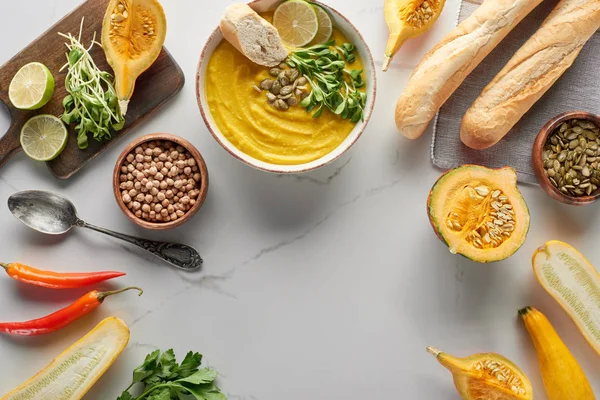 Vue de dessus de la soupe de citrouille en purée automnale sur la surface de marbre avec des ingrédients — Photo de stock