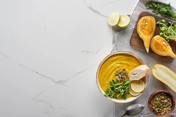 Vista superior de sopa de calabaza triturada otoñal sobre tabla de cortar de madera sobre superficie de mármol - foto de stock