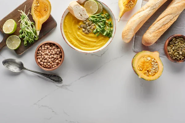 Top view of autumnal pumpkin soup on wooden cutting board on marble surface — Stock Photo