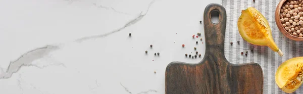 Панорамный снимок деревянной доски с тыквой, горохом и перцем на мраморной поверхности — стоковое фото