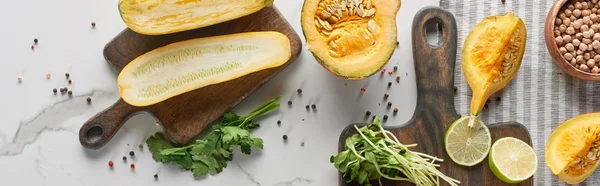 Panoramic shot of zucchini, pumpkin and sprouts on wooden cutting boards on marble surface — Stock Photo