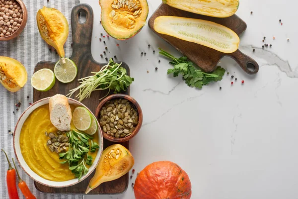 Top view of autumnal mashed pumpkin soup on wooden cutting board on marble surface — Stock Photo