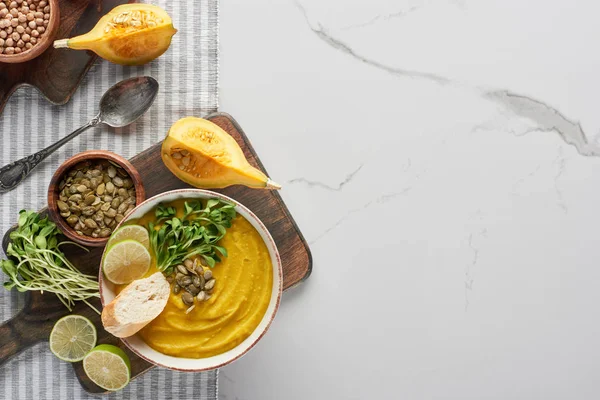 Top view of autumnal mashed pumpkin soup on wooden cutting board on marble surface — Stock Photo