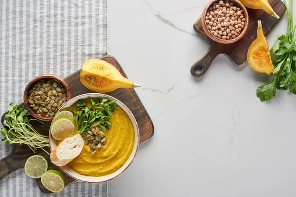 Top view of autumnal mashed pumpkin soup on wooden cutting board on striped napkin — Stock Photo