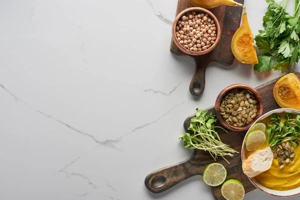 Vista superior da sopa de abóbora purê outonal na placa de corte de madeira na superfície de mármore com ingredientes — Fotografia de Stock