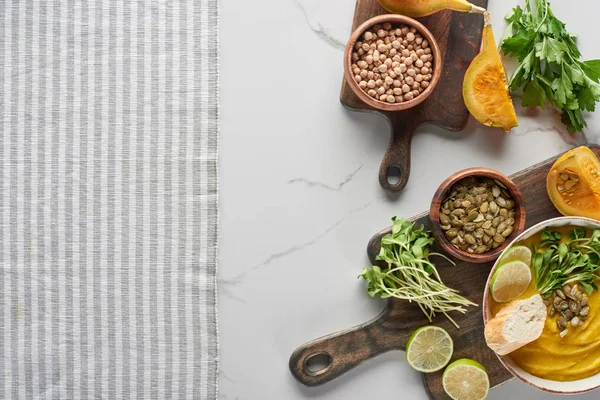 Vue du dessus de la soupe de citrouille en purée automnale sur une planche à découper en bois près d'une serviette rayée — Photo de stock