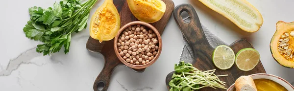 Panoramic shot of autumnal mashed pumpkin soup on wooden cutting board on marble surface — Stock Photo