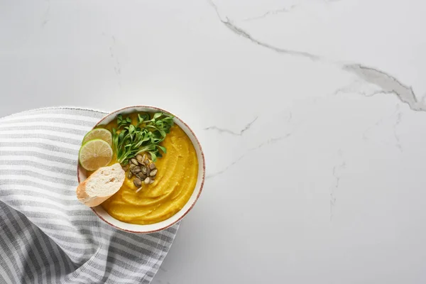 Top view of tasty mashed pumpkin soup near striped napkin on marble surface — Stock Photo