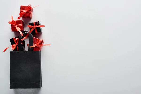 Vista superior del bolso negro con cajas de regalo decorativas sobre fondo blanco — Stock Photo