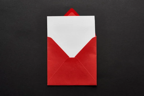 Top view of blank card in red envelope on black background — Stock Photo