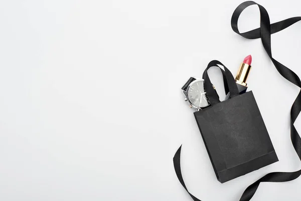 Draufsicht auf kleine Einkaufstasche mit männlicher Armbanduhr und weiblichem Lippenstift in der Nähe des Bandes auf weißem Hintergrund — Stockfoto