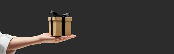 Vista recortada de la mujer sosteniendo caja de regalo en la mano aislado en negro, plano panorámico - foto de stock