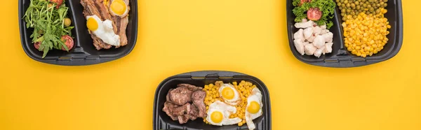 Plano panorámico de paquetes ecológicos con verduras, carne, huevos fritos y ensaladas aisladas en amarillo - foto de stock