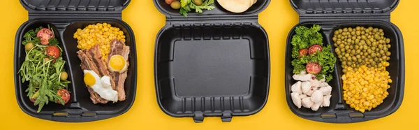 Plano panorámico de paquetes ecológicos con verduras, carne, huevos fritos y ensaladas aisladas en amarillo - foto de stock