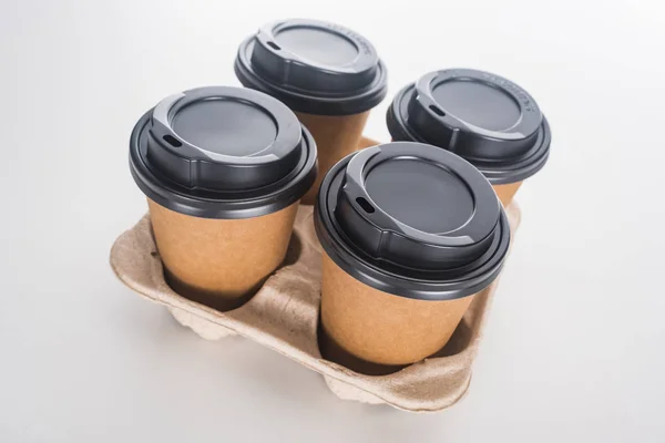 Tazas de papel con café en bandeja de cartón sobre fondo blanco - foto de stock