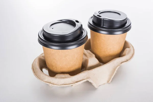 Paper cups with coffee in cardboard tray on white background — Stock Photo