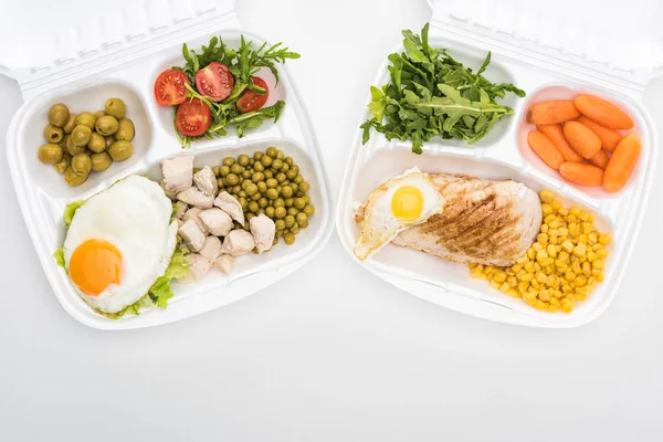 Vista dall'alto di pacchetti eco con rucola, verdure, carne, uova fritte e insalata su sfondo bianco — Foto stock