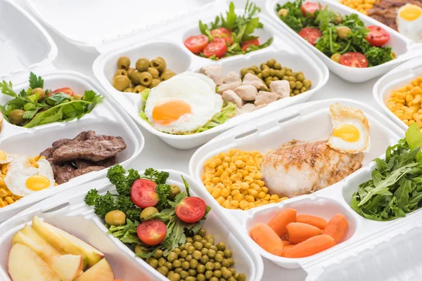 Pacotes ecológicos com maçãs, legumes, carne, ovos fritos e saladas em fundo branco — Fotografia de Stock