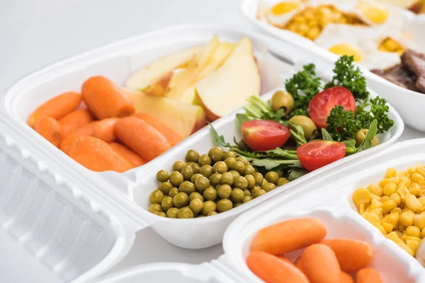 Enfoque selectivo del paquete ecológico con verduras, manzanas y ensalada sobre fondo blanco - foto de stock