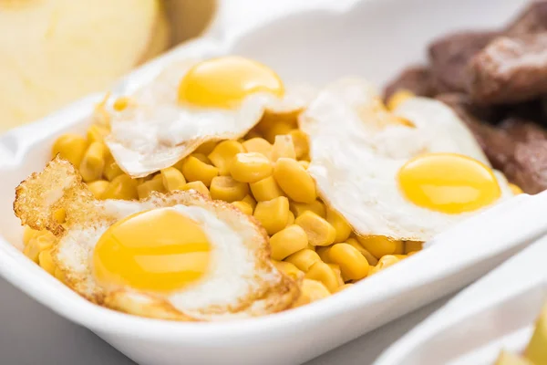 Focus selettivo del pacchetto eco con mais e uova fritte su sfondo bianco — Foto stock