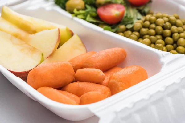 Enfoque selectivo del paquete ecológico con verduras, manzanas y ensalada sobre fondo blanco - foto de stock