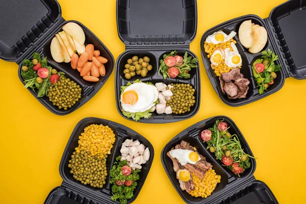 Vista superior de los paquetes ecológicos con manzanas, verduras, carne, huevos fritos y ensaladas aisladas en amarillo — Stock Photo