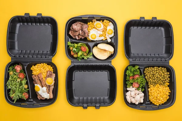 Vue de dessus des emballages écologiques avec pommes, légumes, viande, œufs frits et salades isolés sur jaune — Photo de stock