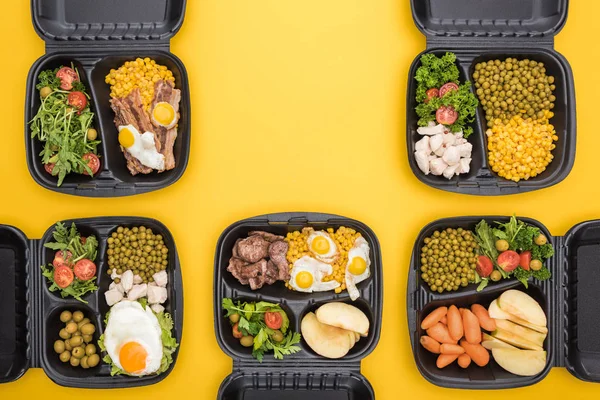 Ansicht der Ökopakete mit Äpfeln, Gemüse, Fleisch, Spiegeleiern und Salaten isoliert auf gelb — Stockfoto