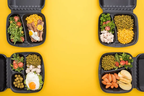 Vista superior de los paquetes ecológicos con manzanas, verduras, carne, huevos fritos y ensaladas aisladas en amarillo - foto de stock