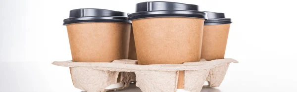 Panoramaaufnahme von Pappbechern mit Kaffee in Papptablett auf weißem Hintergrund — Stockfoto