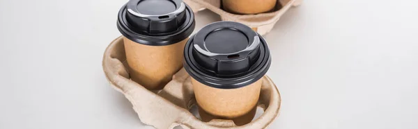 Panoramic shot of paper cups with coffee in cardboard tray on white background — Stock Photo