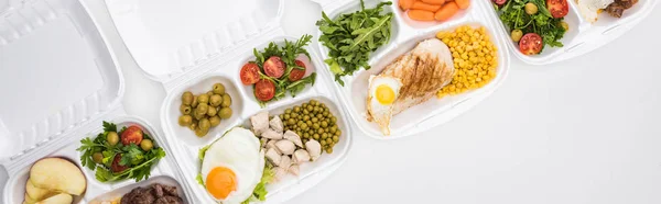 Plano panorámico de paquetes ecológicos con manzanas, verduras, carne, huevos fritos y ensaladas sobre fondo blanco - foto de stock