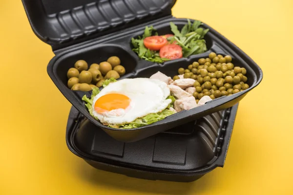 Эко пакет с овощами, мясом, жареным яйцом и салатом изолированы на желтый — стоковое фото
