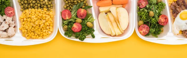 Plano panorámico de paquetes ecológicos con verduras, manzanas, carne, huevo frito y ensaladas aisladas en amarillo - foto de stock