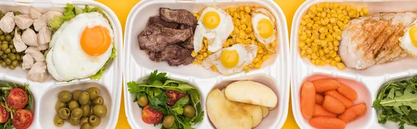 Plano panorámico de paquetes ecológicos con verduras, manzanas, carne, huevos fritos y ensaladas aisladas en amarillo - foto de stock