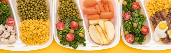 Plano panorámico de paquetes ecológicos con verduras, manzanas, carne, huevos fritos y ensaladas aisladas en amarillo - foto de stock