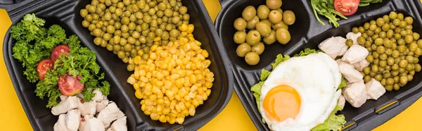 Colpo panoramico di confezioni eco con verdure, carne, uova fritte e insalata isolate su giallo — Foto stock