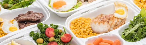 Plano panorámico de paquetes ecológicos con verduras, carne, huevos fritos y ensaladas sobre fondo blanco — Stock Photo