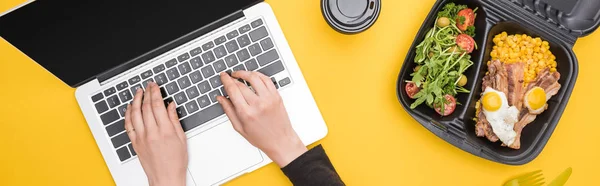 Panoramic shot of woman using laptop with eco package isolated on yellow — Stock Photo