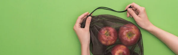 Vista recortada de la mujer sosteniendo manzanas en bolsa ecológica aislado en verde, tiro panorámico - foto de stock