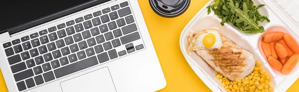 Tiro panorâmico de laptop e pacote ecológico com legumes, carne, ovo frito e rúcula isolada em amarelo — Fotografia de Stock